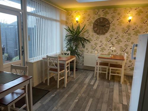 a dining room with two tables and a clock on the wall at Maple Leaf Guest House in Bristol