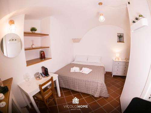 a small bedroom with a bed and a table at Vicolo Home in Putignano