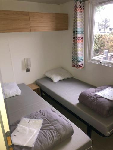 deux lits dans une chambre avec une fenêtre dans l'établissement Mobil Home Premium 6 personnes, à Torreilles
