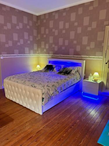 - une chambre dotée d'un lit avec des lumières bleues dans l'établissement Les Trois Tilleuls 2, à Loupiac-de-Cadillac