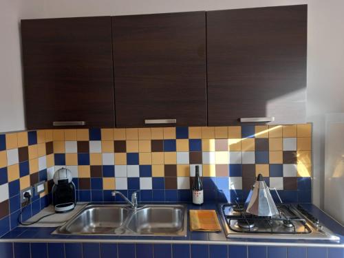 a kitchen with a sink and a tile back splash at Gemme di Portorosa in Furnari