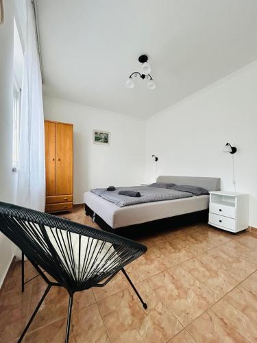 a bedroom with a bed and a chair in it at Szabo Laszlo Vip Apartman in Hajdúszoboszló