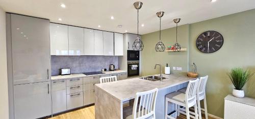 a kitchen with white cabinets and a large clock on the wall at Riverview Apartments by Switchback Stays in Cardiff