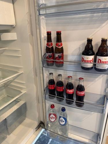 a refrigerator filled with lots of bottles of soda at Zen Retreat met jacuzzi in Grez-Doiceau