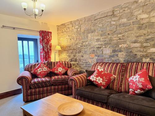 a living room with two couches and a stone wall at Standlow Farm in Kniveton