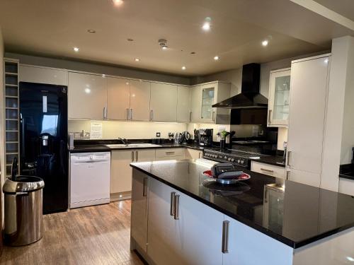 a large kitchen with white cabinets and black counter tops at Standlow Farm in Kniveton