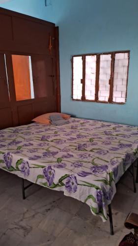 a bed in a bedroom with a purple bedspread at Kanha's Kunj in Prayagraj