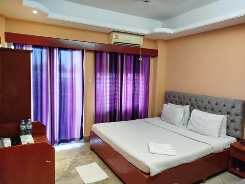 a bed in a room with purple curtains at The Divine Eco Resort in Cox's Bazar