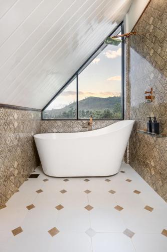 a bath tub in a bathroom with a window at The Chapter in Nuwara Eliya
