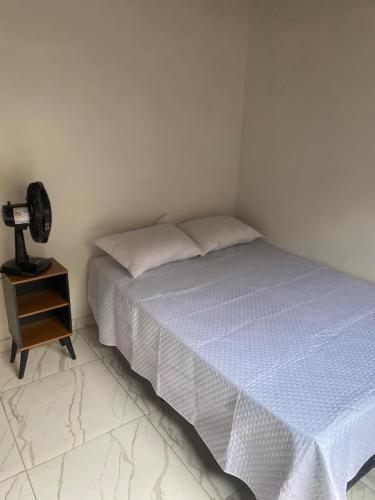 a bedroom with a bed and a lamp on a night stand at Casa aconchegante em Barra de Caravelas in Caravellas