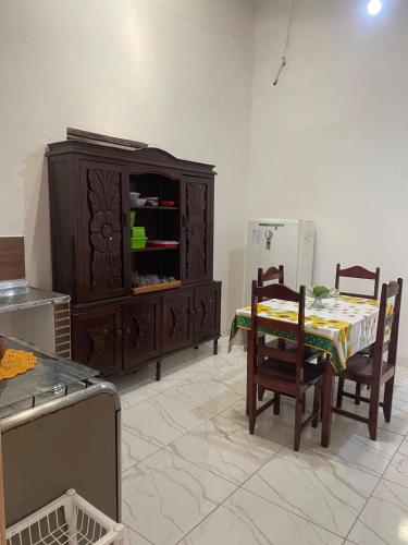 a kitchen with a table and a cabinet and a table and chairs at Casa aconchegante em Barra de Caravelas in Caravellas