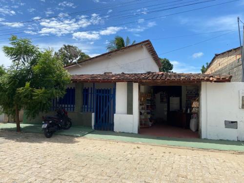 a small white house with a motorcycle parked outside at Casa aconchegante em Barra de Caravelas in Caravellas