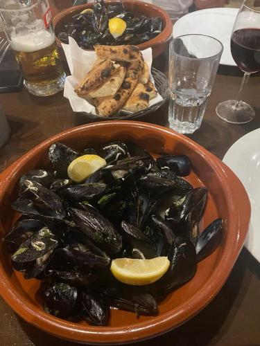a bowl of mussels with lemons on a table at Apartman AS in Pirovac