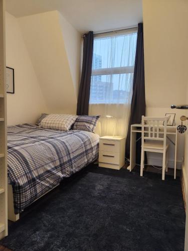 a bedroom with two beds and a window with a chair at Modern Spacious Rooms 10 Minutes from Big Ben in London