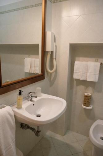 a bathroom with a sink and a mirror and a toilet at Hotel Elios Tao in Taormina