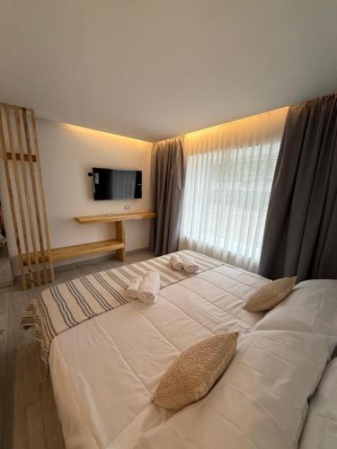 a large white bed in a room with a window at Los Cardos Lodge & Glamping in Malargüe