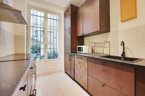 une cuisine avec un évier et un micro-ondes dans l'établissement Spacious apartment - 3BR-8P - Ternes, à Paris