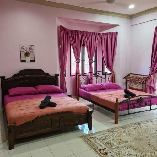 two beds in a room with pink curtains at Sayf Homestay Kuala Terengganu in Kuala Terengganu