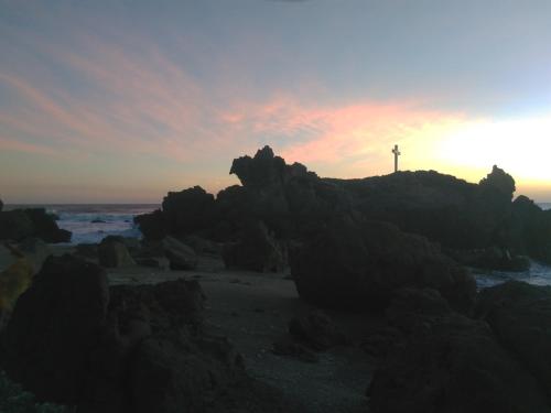 a lighthouse on a rocky beach at sunset at El Belga Loco in Las Peñitas