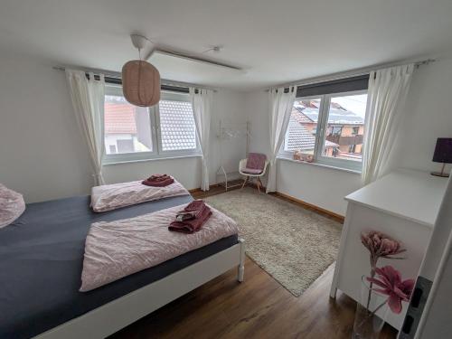 a bedroom with two beds and two windows at fewoflagmeier Meidelstetten I Maisonetten Wohnung Alb in Hohenstein
