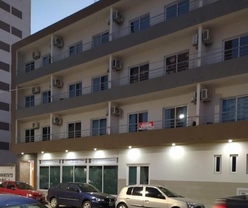 Un gran edificio con coches aparcados delante. en Casa de playa monoambiente, en Necochea