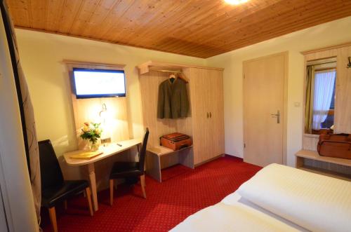 a hotel room with a desk and a bed and a bedroom at Gästehaus Sonnenbichl in Fischbachau