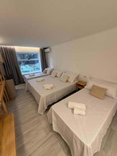 a room with three beds with white sheets at Los Cardos Lodge & Glamping in Malargüe