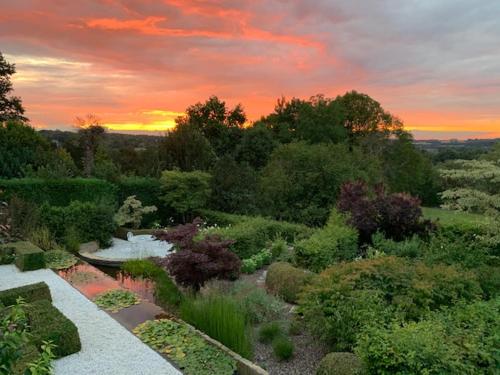 a garden with a sunset in the background at Zen Retreat met jacuzzi in Grez-Doiceau