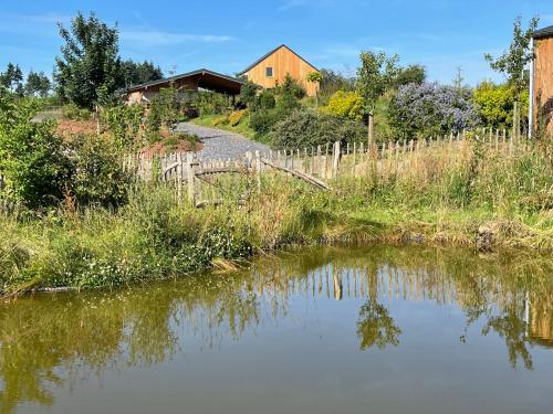 a pond with a fence and a house in the background at Les Gîtes de la Préale in Achet