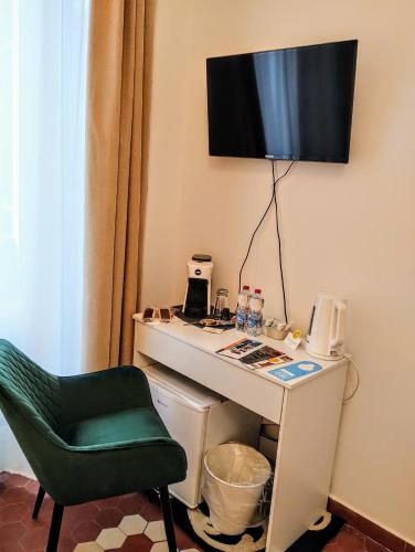 a desk with a green chair and a television on a wall at Suleima B&B Messina Centro in Messina