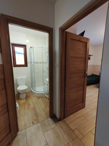 a bathroom with a toilet and a wooden door at Bieszczadzkie Brzegi in Ustrzyki Dolne