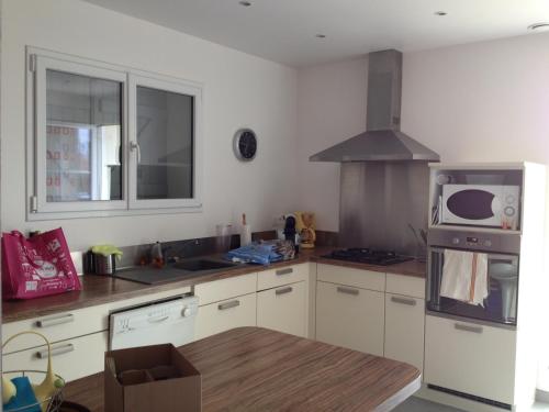 une cuisine avec des armoires blanches et un micro-ondes dans l'établissement Villa œillets des dunes, à Capbreton