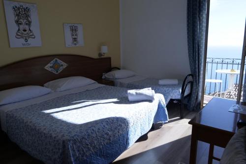 a bedroom with two beds and a balcony at Hotel Elios Tao in Taormina