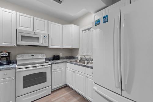 a kitchen with white cabinets and a white refrigerator at Outer Banks Haven New Kitchen and New Outdoor Areas in Kitty Hawk Beach