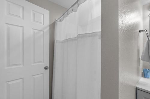 a bathroom with a shower with a white shower curtain at Outer Banks Haven New Kitchen and New Outdoor Areas in Kitty Hawk Beach