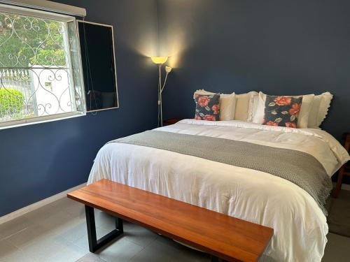 1 dormitorio con 1 cama con banco de madera junto a una ventana en Suíte espaçosa em bairro bem localizado, en Mairiporã