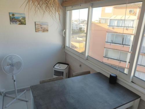 Cette chambre dispose d'un bureau et d'une fenêtre avec un ventilateur. dans l'établissement Studio vacances Cap d 'Agde, au Cap d'Agde