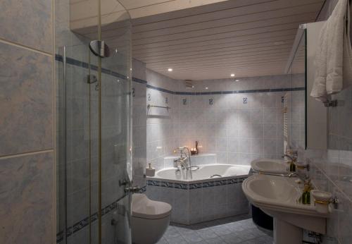 a bathroom with a tub and a toilet and a sink at Chalet Hunnenfluh Garden Apartment in Wengen