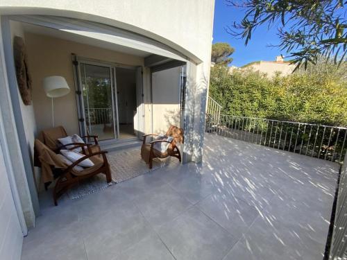 un patio avec deux chaises et un chien assis sur une terrasse couverte dans l'établissement Appartement climatisé en rez-de-chaussée 3 personnes max, au Cap d'Agde