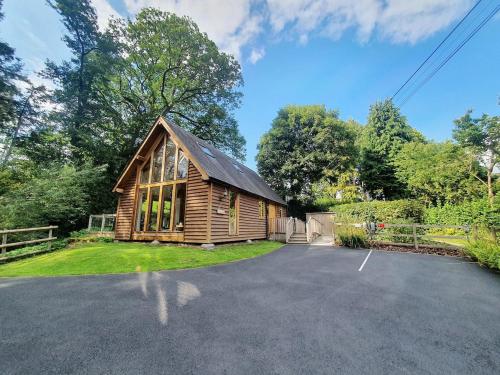 a log cabin with a driveway in front of a house at Swn Y Nant Lodge with hot tub Brecon in Brecon