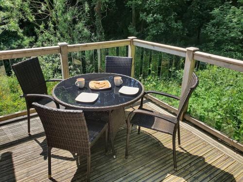 a table with chairs and a plate of food on a deck at Swn Y Nant Lodge with hot tub Brecon in Brecon