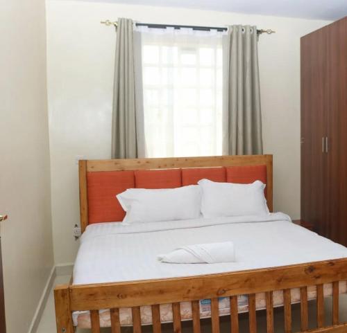 a wooden bed with white pillows and a window at Boffar 4 bedroom units in Naivasha