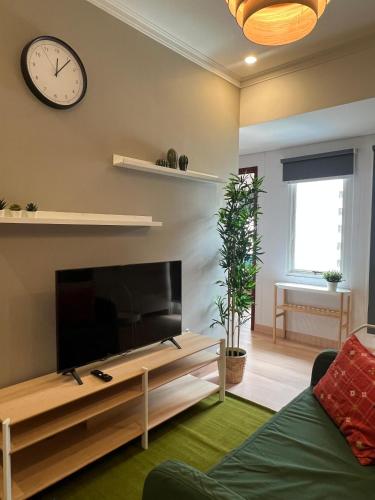 a living room with a large television and a clock at Royal Deluxe & Private Apartments - West Jakarta in Jakarta