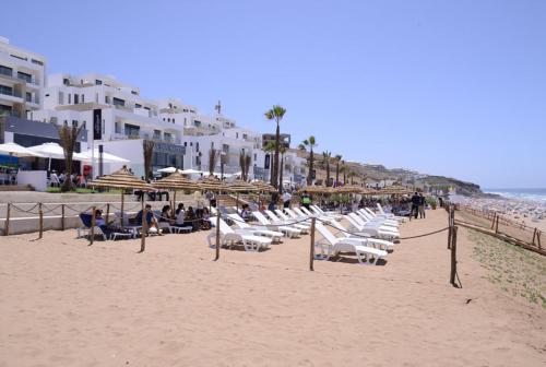a beach with chairs and umbrellas and the ocean at Nice apartment by the beach in Sale