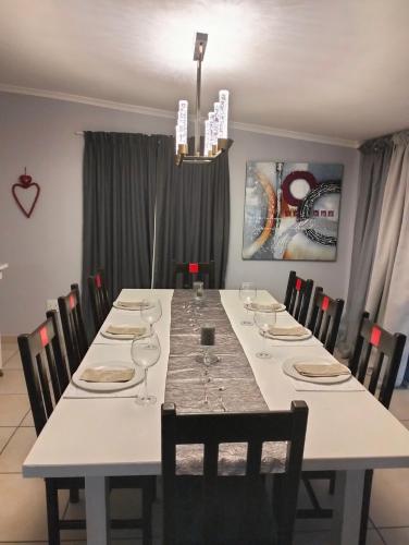 a dining room with a long table with wine glasses at 25 On Main Struisbaai in Struisbaai