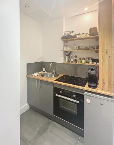 une cuisine avec un évier et une cuisinière dans l'établissement So Guest, Clou dans le fer, modern suite near cathedral, à Reims