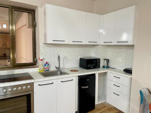 une cuisine avec des armoires blanches et un réfrigérateur noir dans l'établissement Quite and Modern Studio, à Tirana