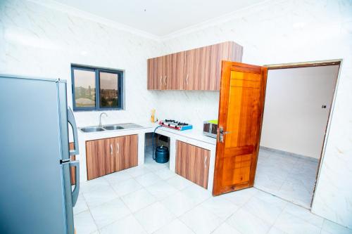 a kitchen with wooden cabinets and a sink and a door at Mike's B&B in Kwabenya