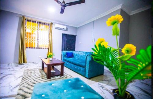 a living room with a blue couch and a table at Mike's B&B in Kwabenya