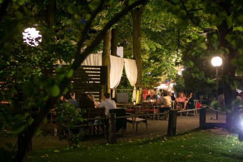people sitting at tables in a park at night at Hotel Milano Pool & Garden in Salice Terme